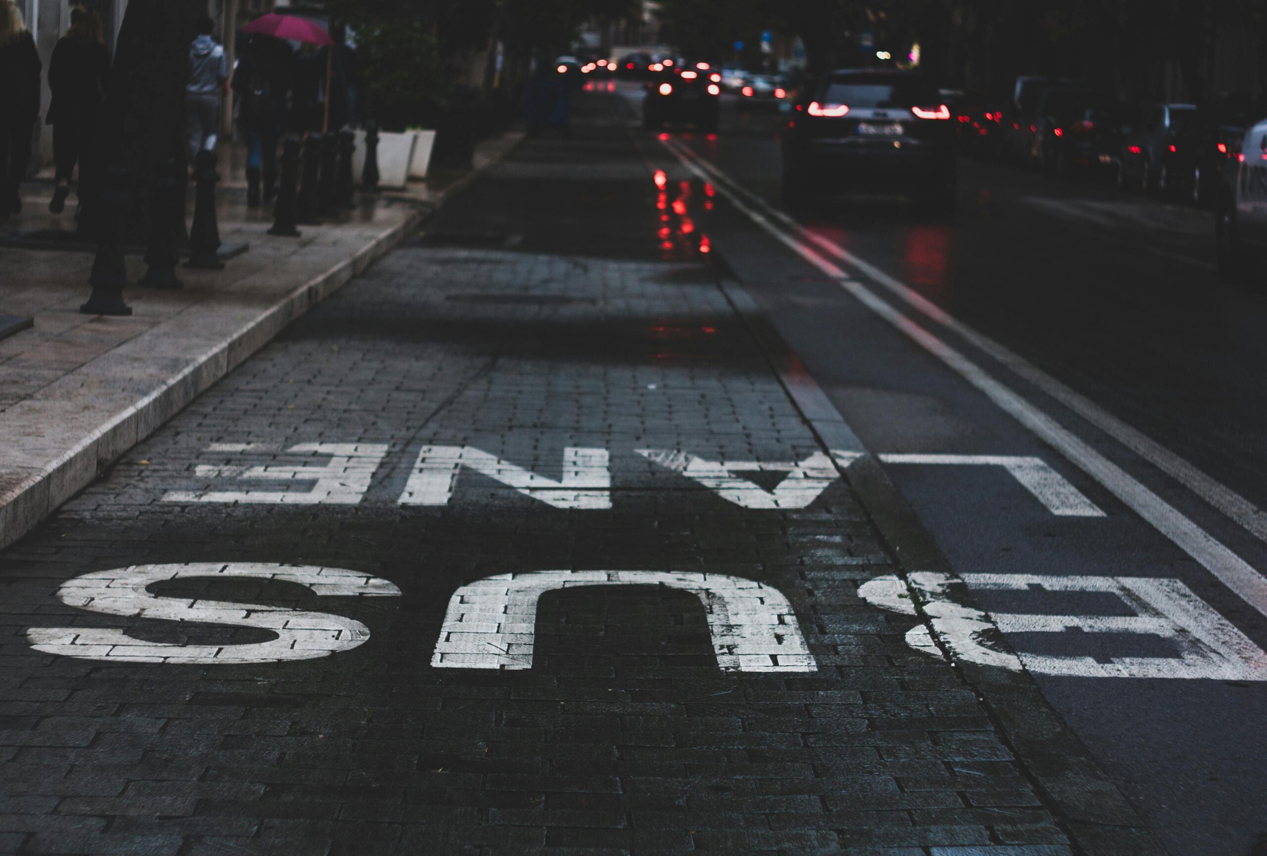 Bus lane signage on a wet urban street at night showcasing urban lifestyle.