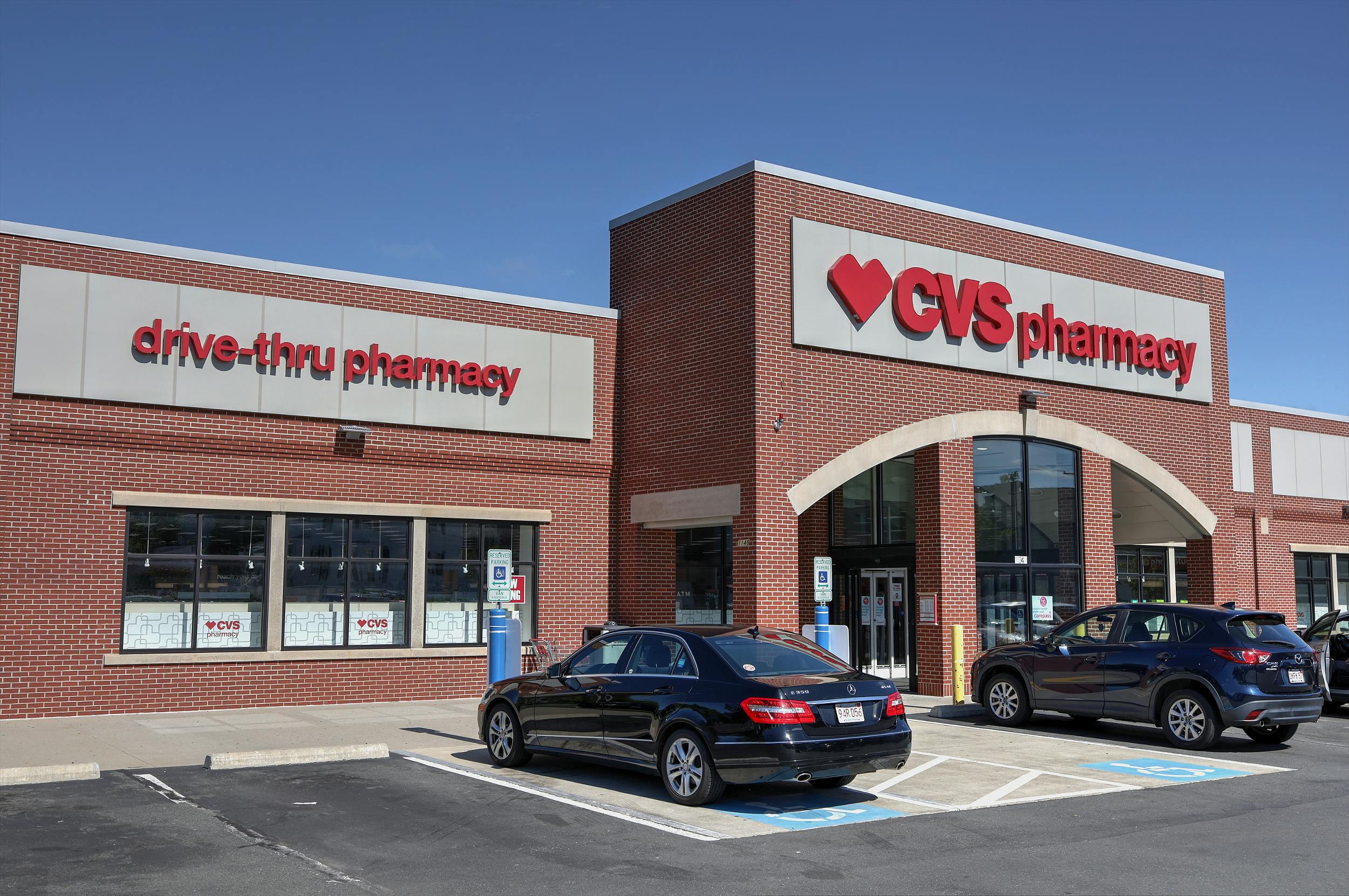 Brick CVS Pharmacy building with drive-thru, cars parked outside.